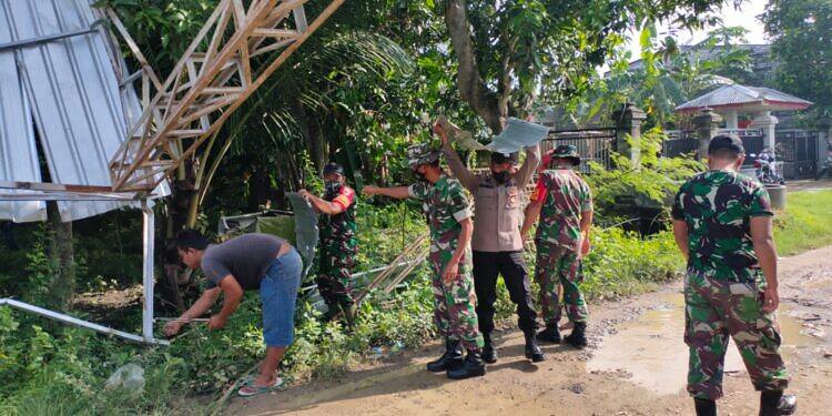 Dengan Sigap Anggota TNI Kecamatan Kedungpring Gotong Royong Bersihkan Puing Gudang yang Diterjang Angin Puting Beliung